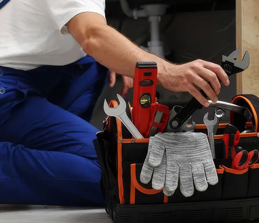 Technician in blue uniform organizing tools and work gloves in a red and black toolbelt.