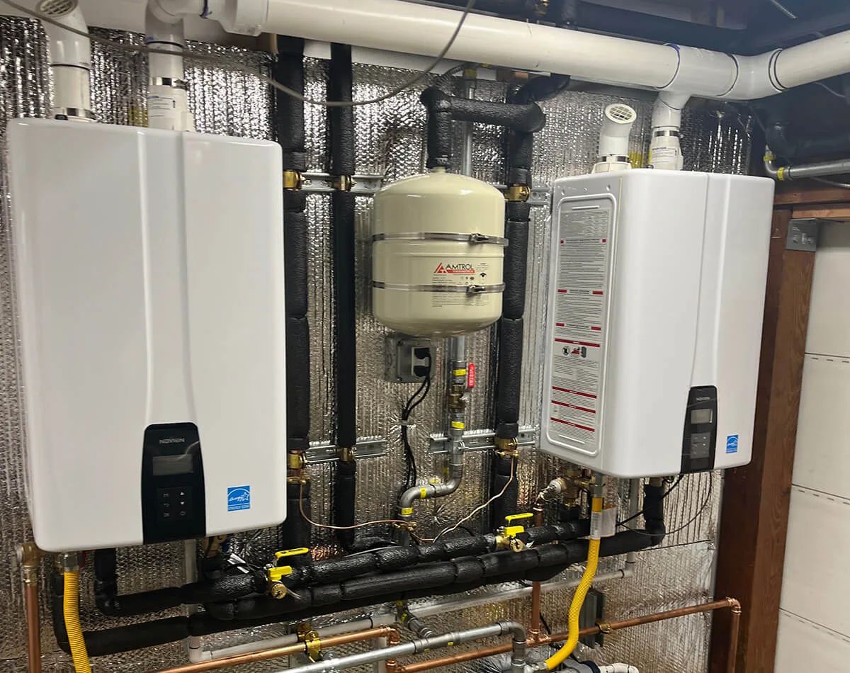 Water filtration and tankless water heater system installed in basement with insulated pipes and yellow shut-off valves.