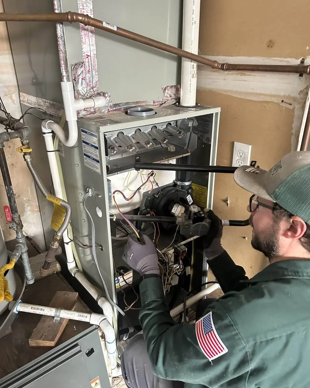An Ongaro & Sons technician servicing a furnace in a utility closet