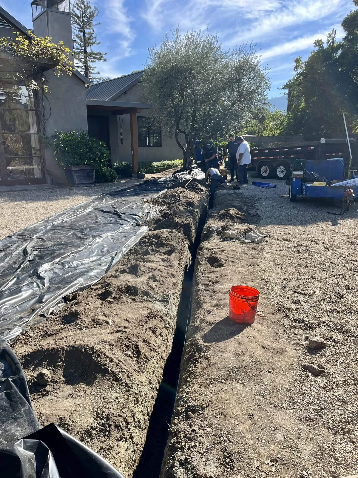 A trench opened across a driveway to replace an underground service line