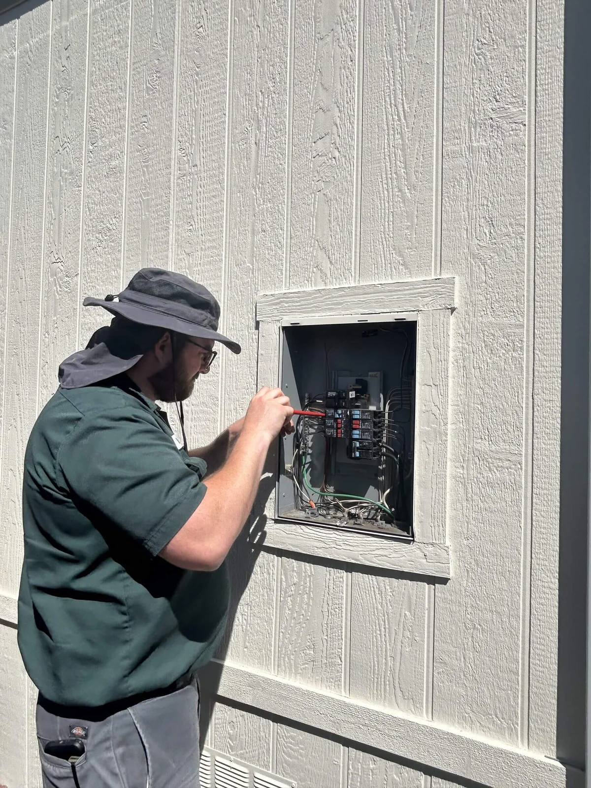 An Ongaro & Sons electrician servicing an exterior subpanel