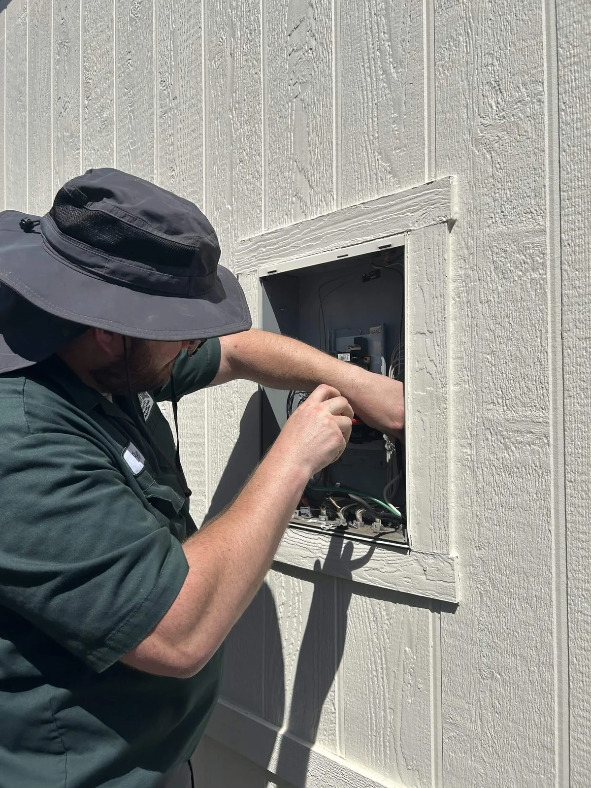 An Ongaro & Sons electrician wiring an exterior junction box