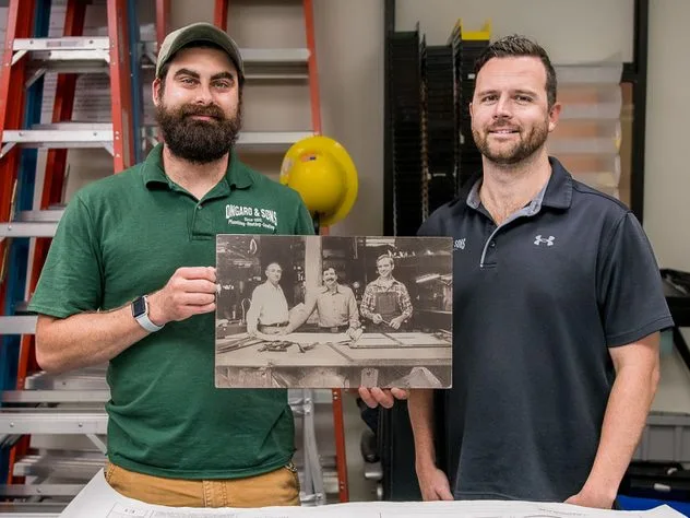 Fourth-generation owners Ernest J. and Donald Ongaro holding a photo of the original shop