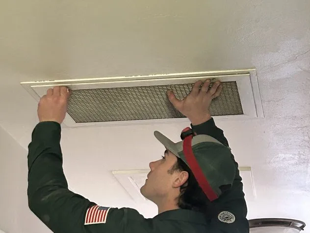 Technician servicing a ceiling return air register