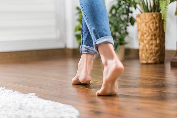 Floor heating. Young woman walking in the house on the warm floor.